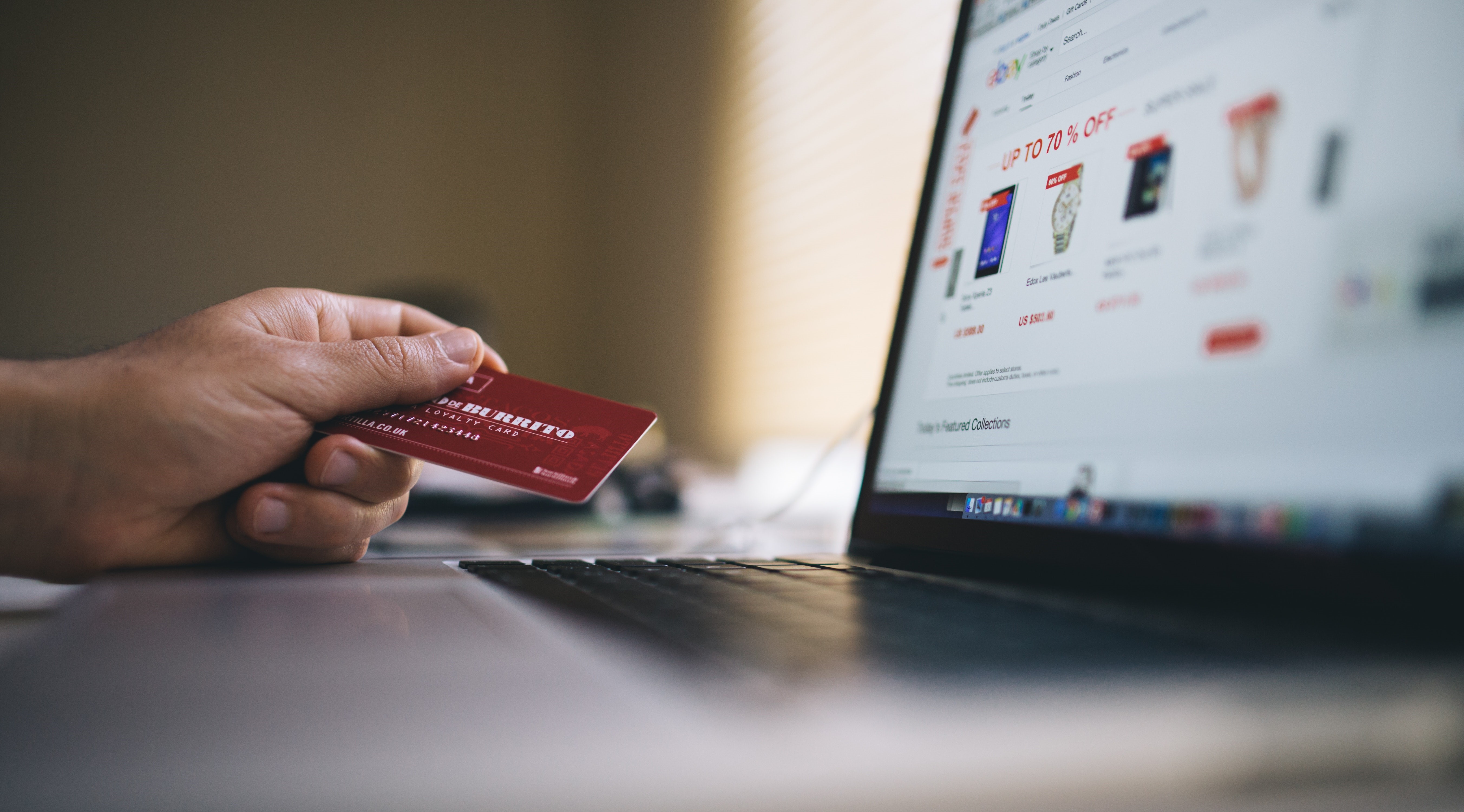 A computer screen with a person holding a bank card indicating that they are preparing to buy something online. 