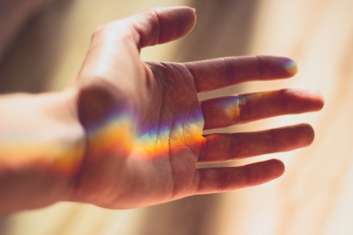 A hand with a rainbow projected on to it. 