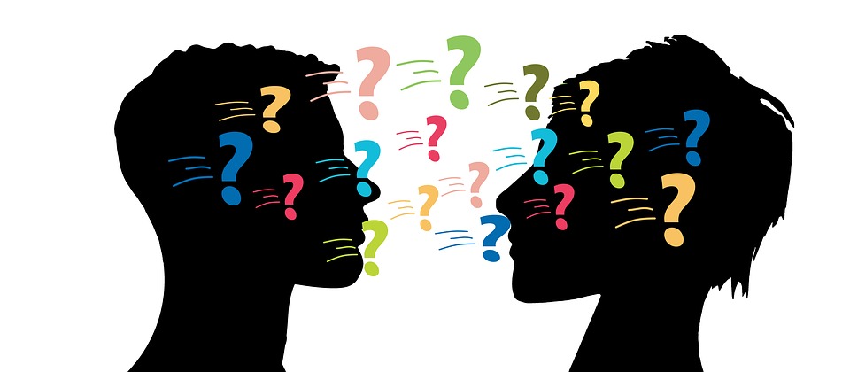 Two silhouettes of people speaking with colourful question marks between them.