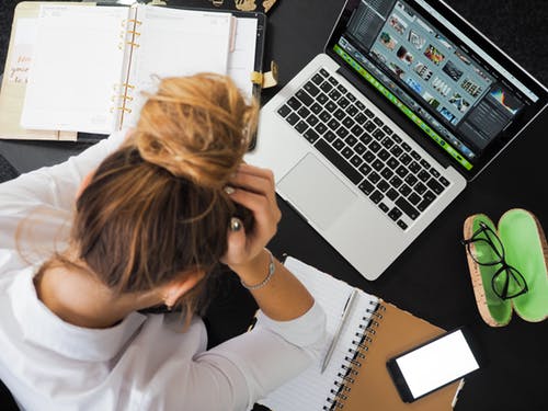 Female working in front of a laptop surrounded by papers - her head cupped in her hands. Female working in front of a laptop surrounded by papers - her head cupped in her hands.